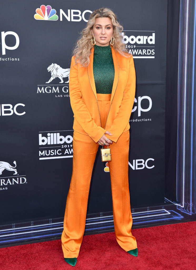 Tori Kelly poses on the red carpet for the 2019 BBMAs. She wore a color blocking tangerine and emerald green look. 