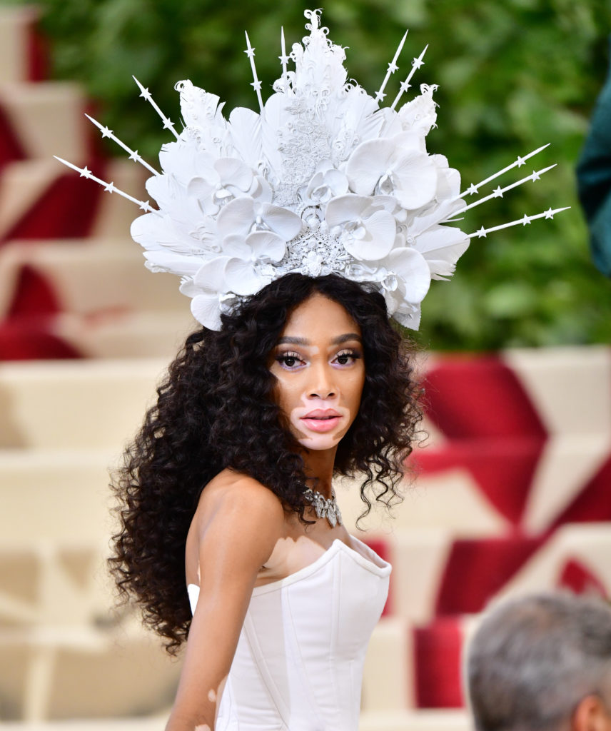 Winnie Harlow attends first Met Gala in 2018. She wore Tommy Hilfiger and a white headpiece designed by Brittny Wood. 